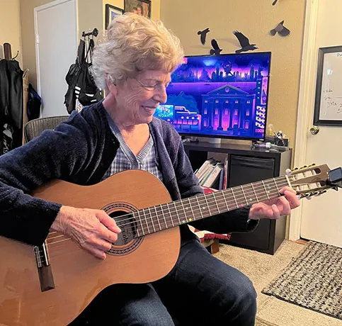 Senior learning acoustic guitar during a relaxed lesson at PlayPro Guitar School