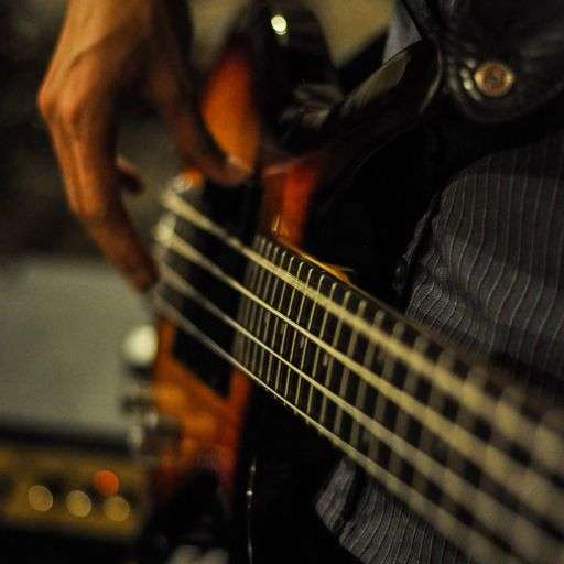 Close up of bass guitar strings being played with fingers