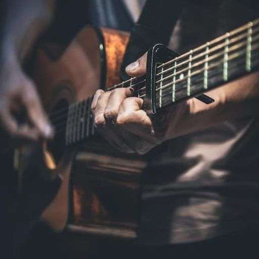 Close-up of hands playing acoustic guitar with fingerstyle technique at PlayPro Guitar School
