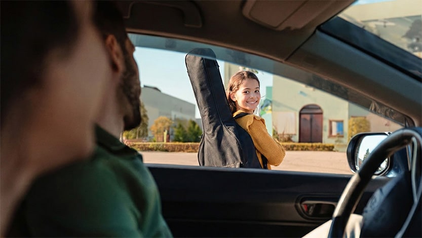 Child with guitar case excited after kids guitar lesson pickup at PlayPro Guitar School La Mesa