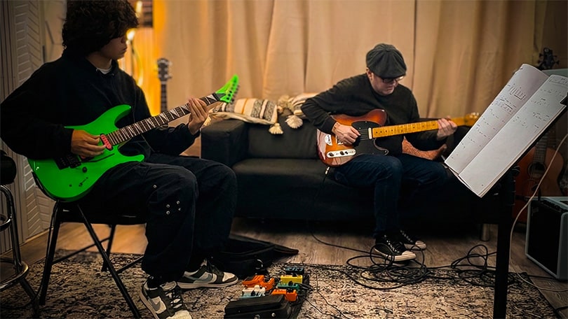 Guitar teacher Jan Parra and student with green guiter practicing with music notation at PlayPro Guitar School in La Mesa California