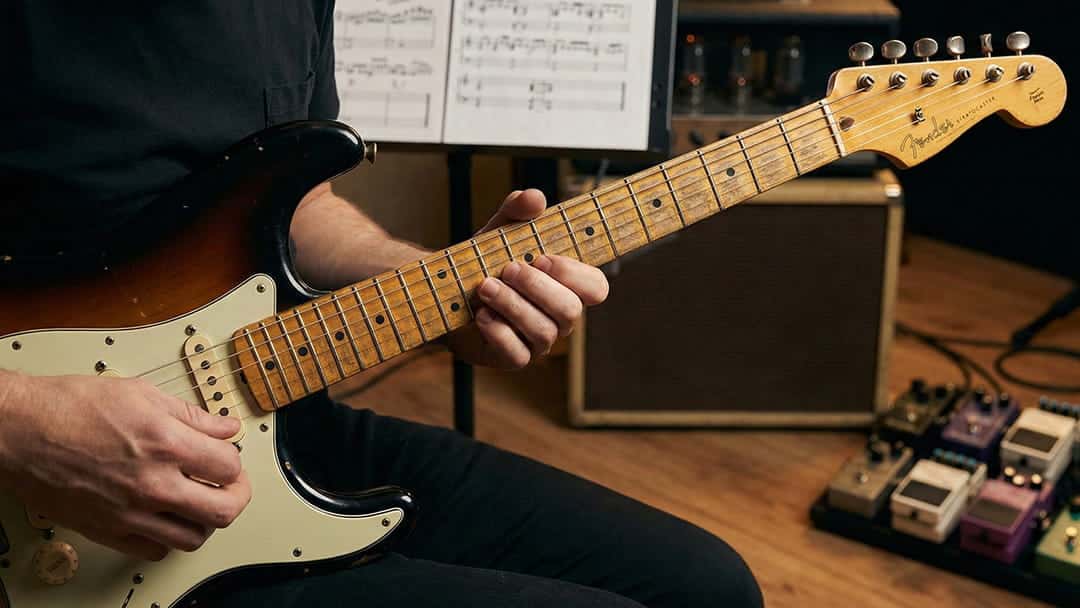 Advanced guitar student working on fretboard technique with amp and notation at PlayPro Guitar School La Mesa