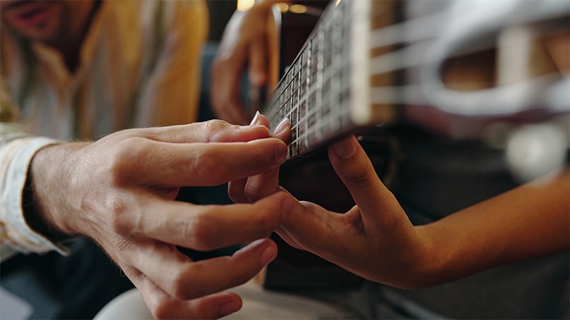 Child learning proper guitar finger positioning and beginner chords during kids guitar lesson in La Mesa