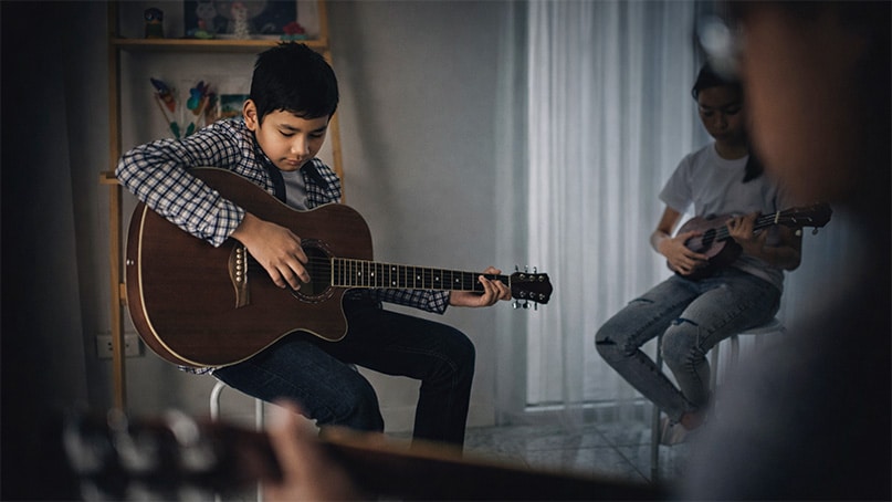 Children learning guitar together during beginner kids guitar lessons at PlayPro Guitar School in La Mesa