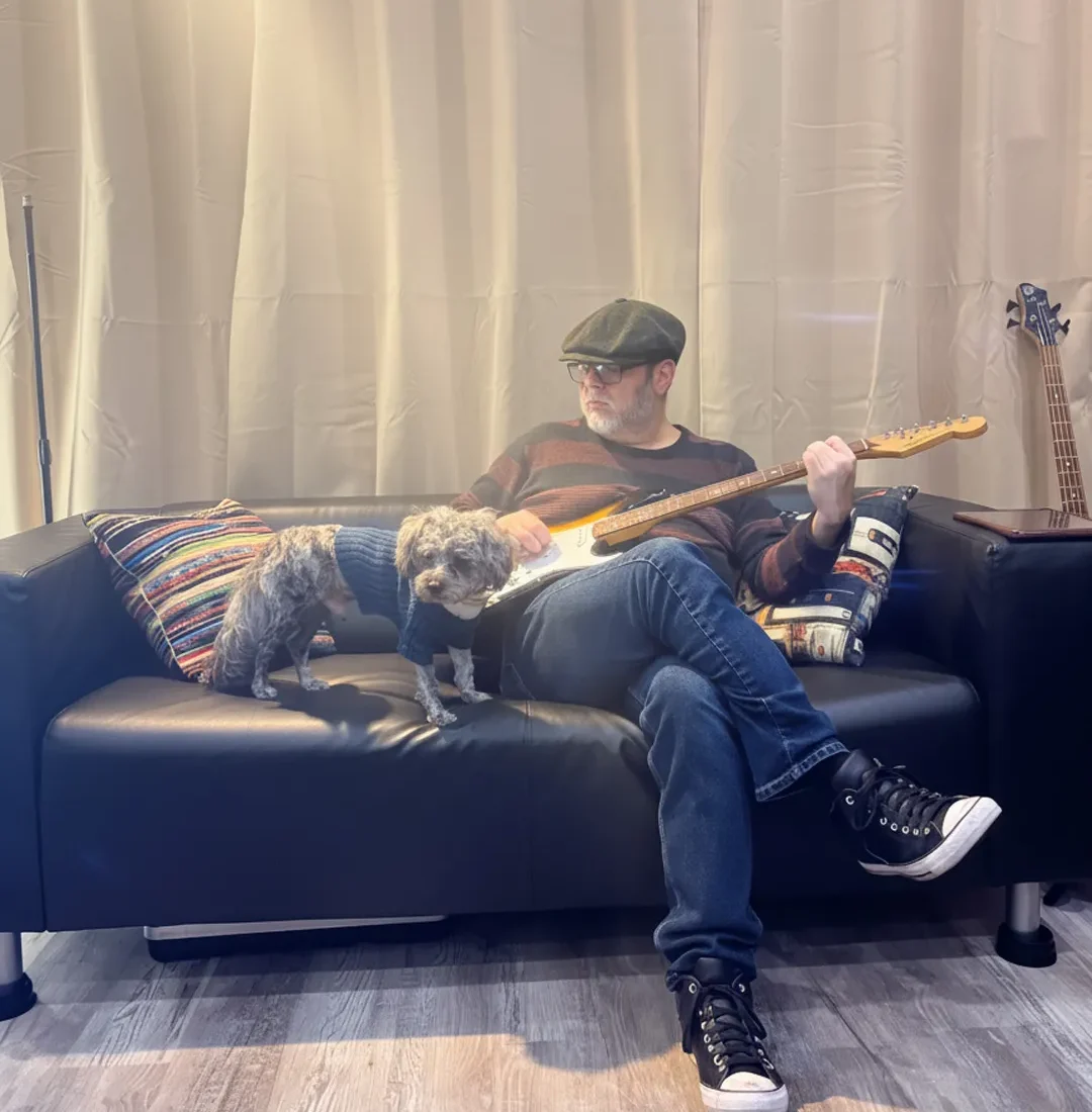 Guitar instructor playing electric guitar on a studio couch during a relaxed lesson environment in La Mesa California
